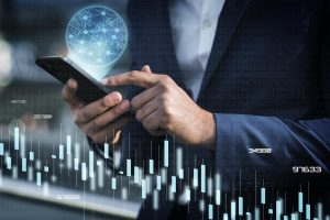 A man in a business suit uses a smartphone with digital data visualizations, bar charts, and a glowing global network hologram hovering above the device. The scene symbolizes the interconnected systems and financial transactions that drive the modern digital economy.