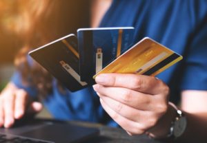 A person holding several colourful credit cards while using a laptop, symbolising consumer choice and the growing popularity of co-branded cards.