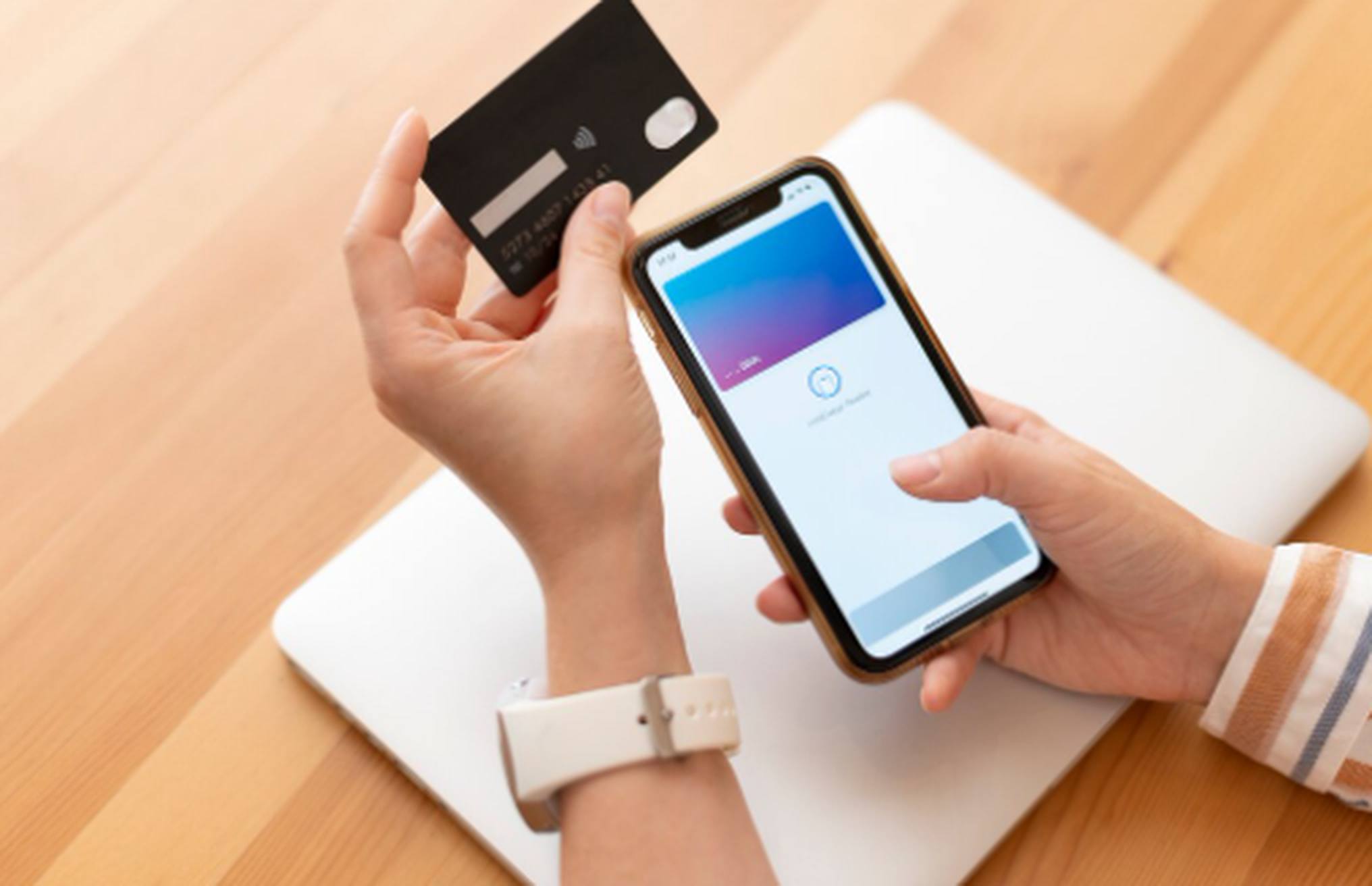 A person holding a credit card and using a smartphone for an online payment, illustrating the convenience and security of digital wallets.