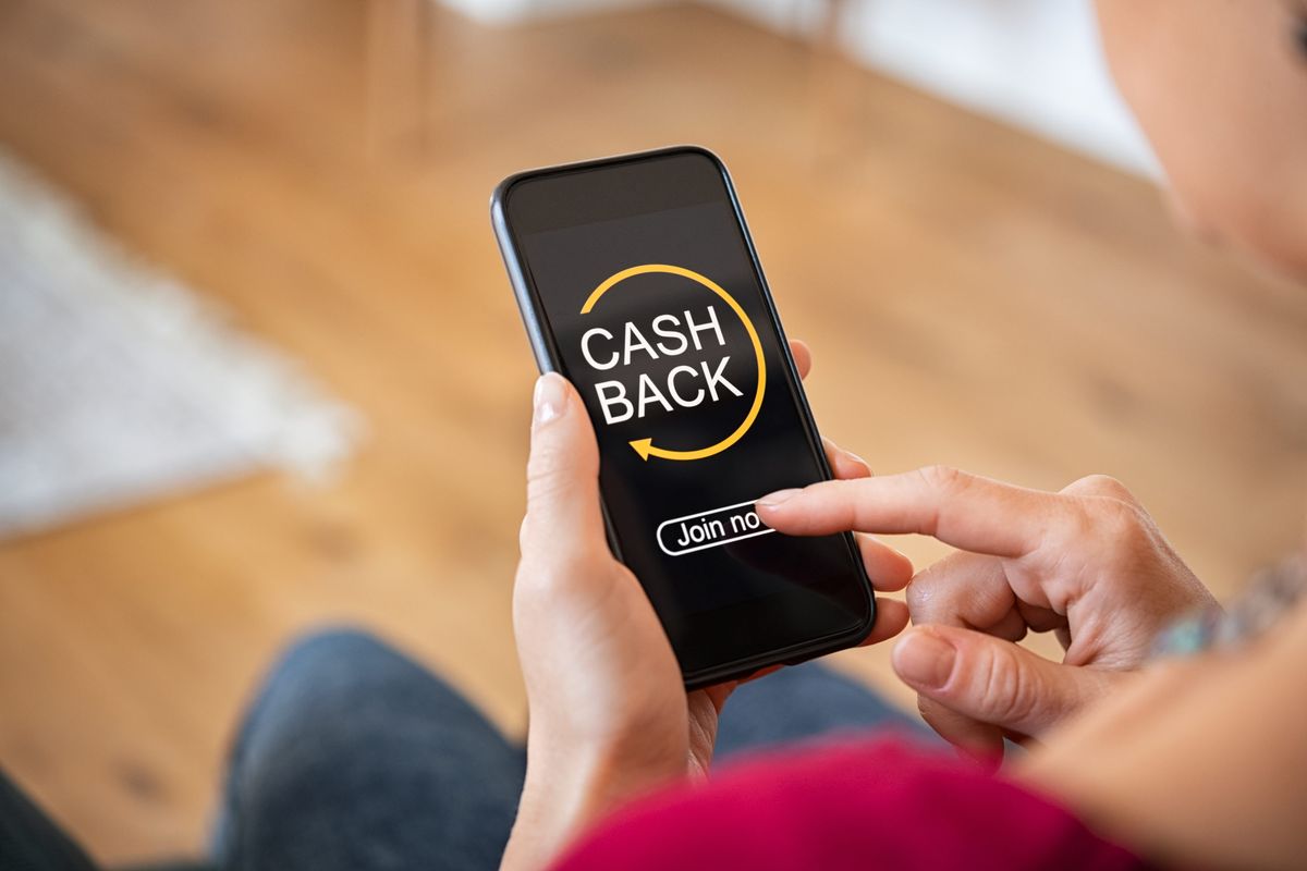 Person holding a smartphone with a cashback app on the screen, symbolizing instant cashback rewards on digital purchases.
